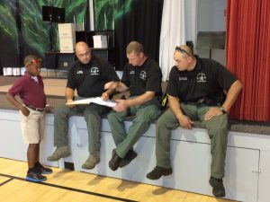 Deputies Chris Pultz, Jonathan Wells and Kenny Randozza signing autographs for student Runako Walsh.