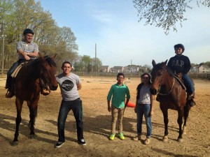 left to right: Domingo Suriel, Andrew Vela and Rebeca Jovel pose with riders from a local horse farm.