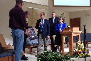 Nathan Greene presenting paintings to Tony Smith, second left, and Eric Spoonseller, left.